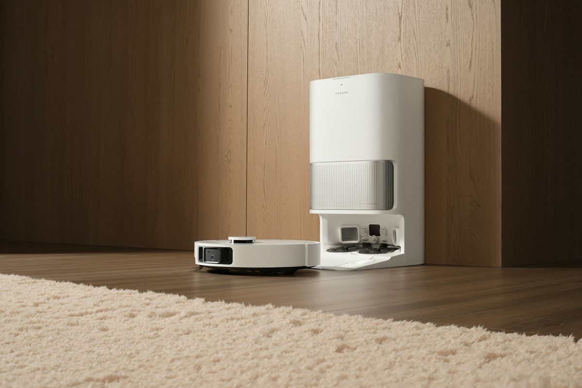 A white robot vacuum parked in a tall white self-emptying dock next to a cream rug